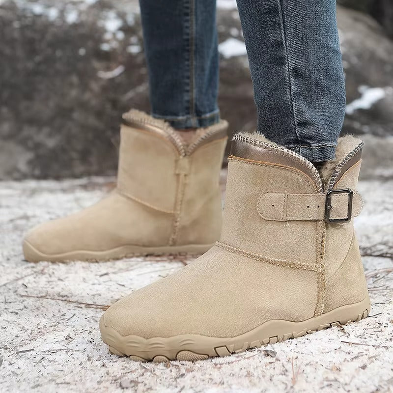 Śniegowce barefoot w kolorze piaskowego beżu na nogach na zaśnieżonym podłożu